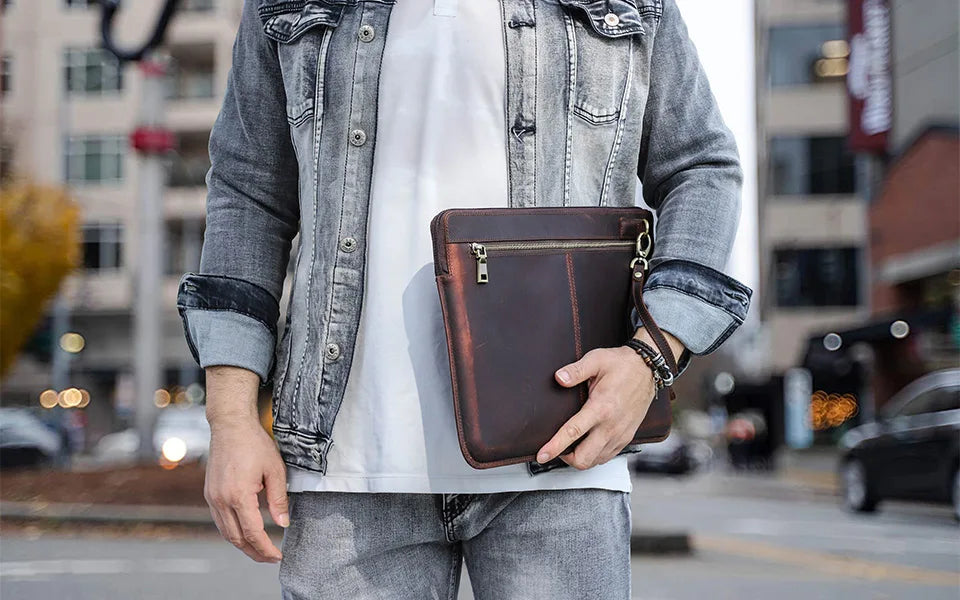 Person holding a brown leather bag in an urban setting