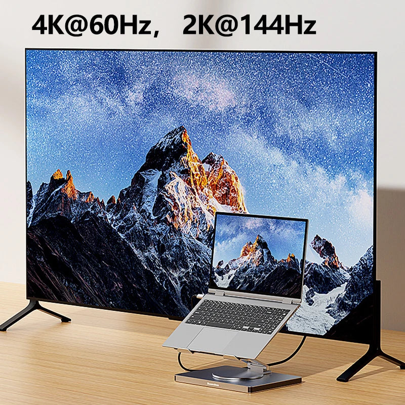 Large monitor displaying mountain scene with laptop showing same image on wooden surface